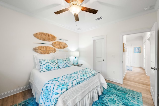 bedroom featuring wood-type flooring, ornamental molding, and ceiling fan