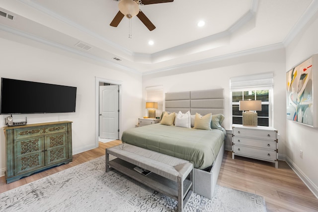 bedroom featuring crown molding, light hardwood / wood-style flooring, a raised ceiling, and ceiling fan