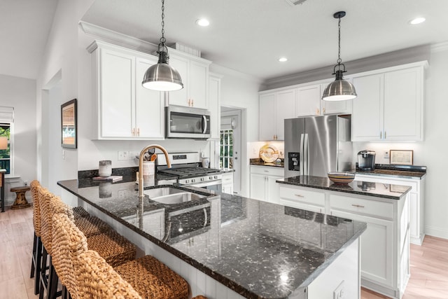 kitchen with sink, appliances with stainless steel finishes, white cabinetry, dark stone countertops, and decorative light fixtures