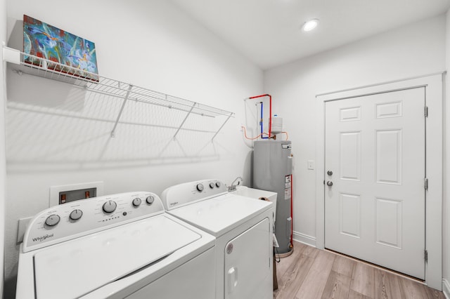 clothes washing area with water heater, light hardwood / wood-style flooring, and independent washer and dryer