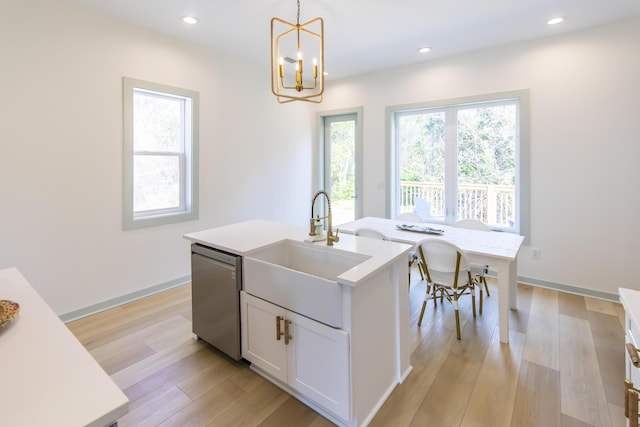 kitchen with pendant lighting, sink, white cabinets, a kitchen island with sink, and stainless steel dishwasher