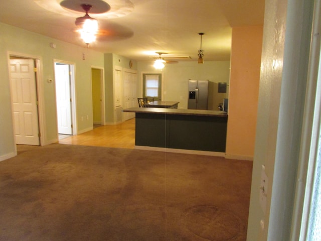 kitchen featuring decorative light fixtures, stainless steel fridge, ceiling fan, kitchen peninsula, and light carpet