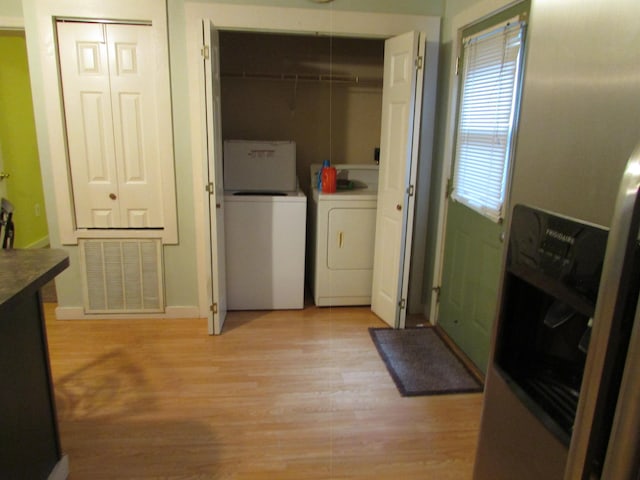 washroom featuring light hardwood / wood-style floors, washer and dryer, and a wealth of natural light