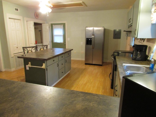 kitchen with a kitchen island, stove, light hardwood / wood-style floors, and stainless steel fridge with ice dispenser