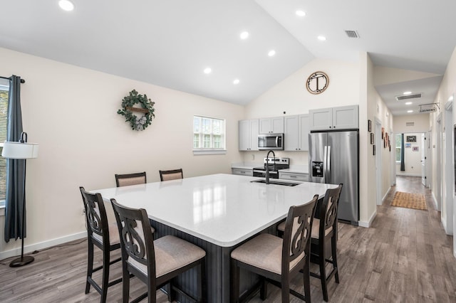 kitchen featuring a kitchen bar, sink, light hardwood / wood-style flooring, appliances with stainless steel finishes, and a large island