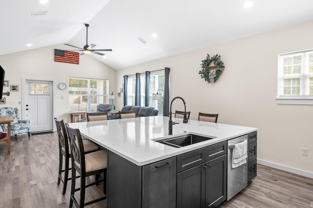 kitchen featuring sink, vaulted ceiling, light hardwood / wood-style flooring, dishwasher, and an island with sink