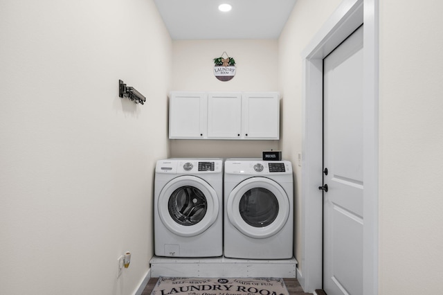 laundry room with cabinets, washing machine and dryer, and wood-type flooring