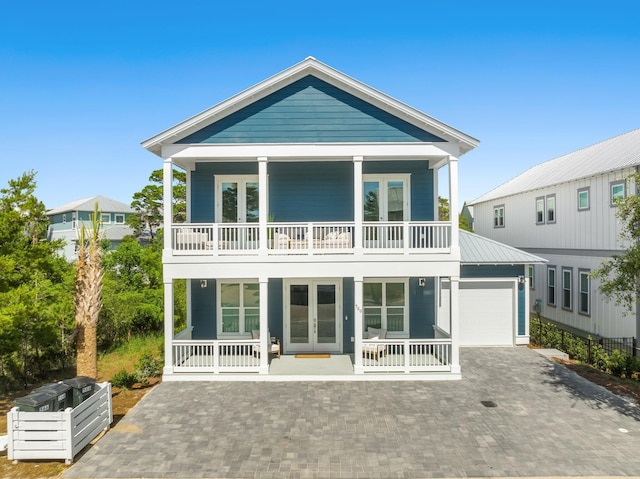 rear view of house featuring a garage, french doors, a balcony, and a porch