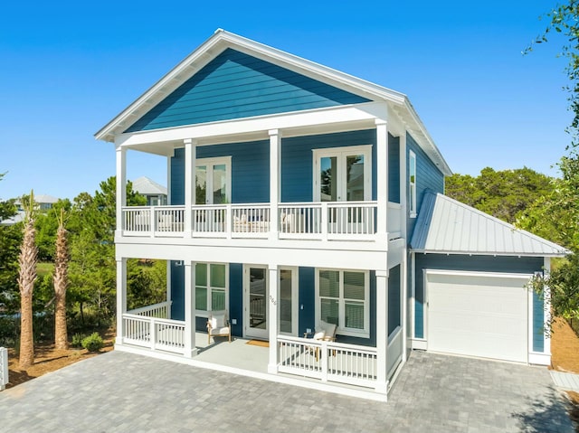 rear view of house with a garage, a balcony, and covered porch