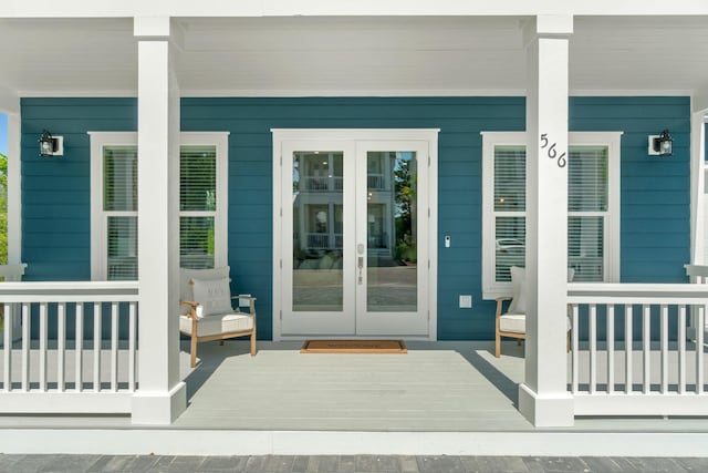 view of exterior entry with covered porch and french doors