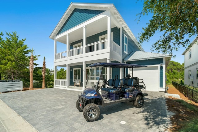 back of house featuring a garage, a balcony, and covered porch