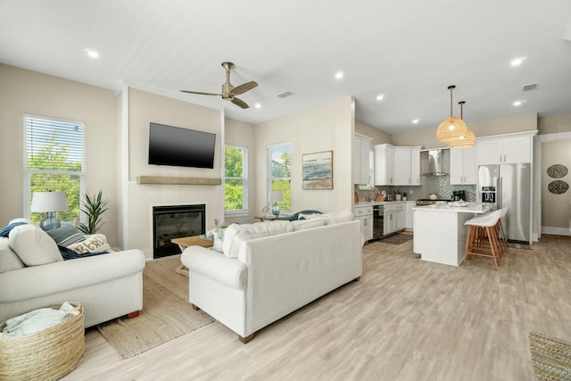 living room featuring light hardwood / wood-style flooring, a wealth of natural light, and ceiling fan