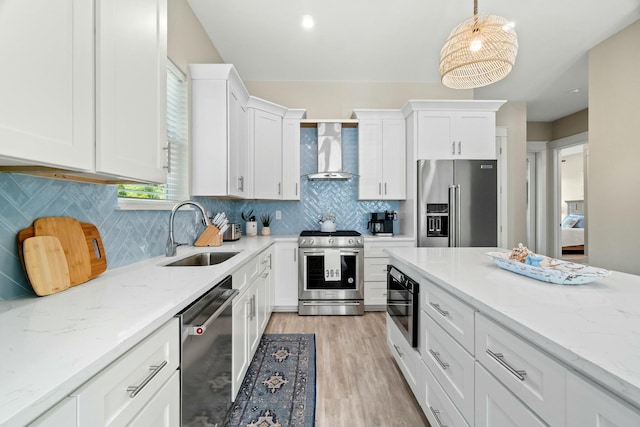 kitchen with wall chimney range hood, sink, white cabinets, and appliances with stainless steel finishes