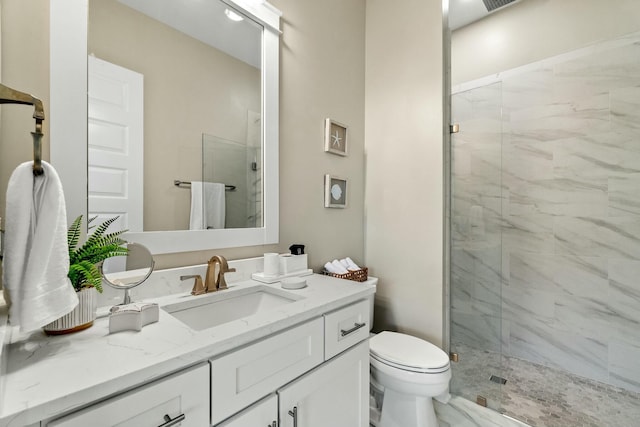 bathroom with a tile shower, vanity, and toilet