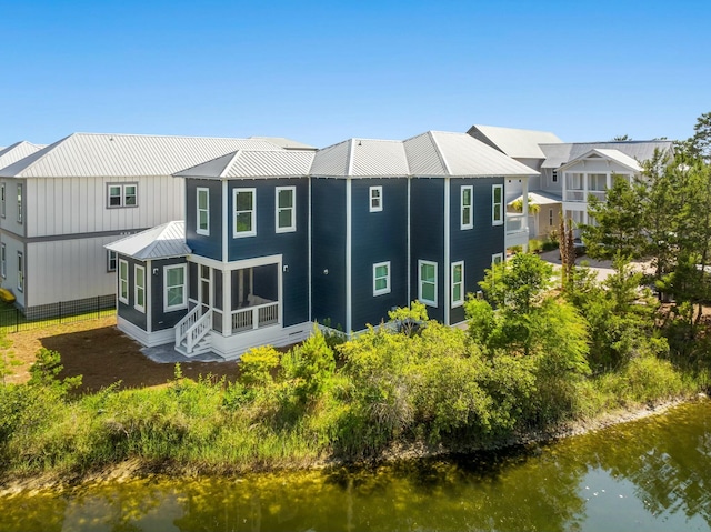 rear view of property with a sunroom and a water view