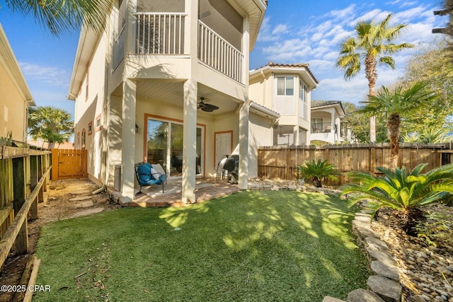 back of house featuring ceiling fan, a patio area, a balcony, and a lawn