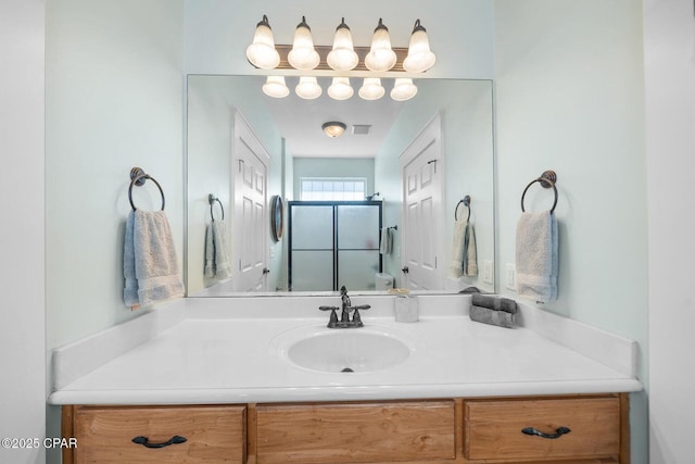 bathroom featuring a shower with door and vanity