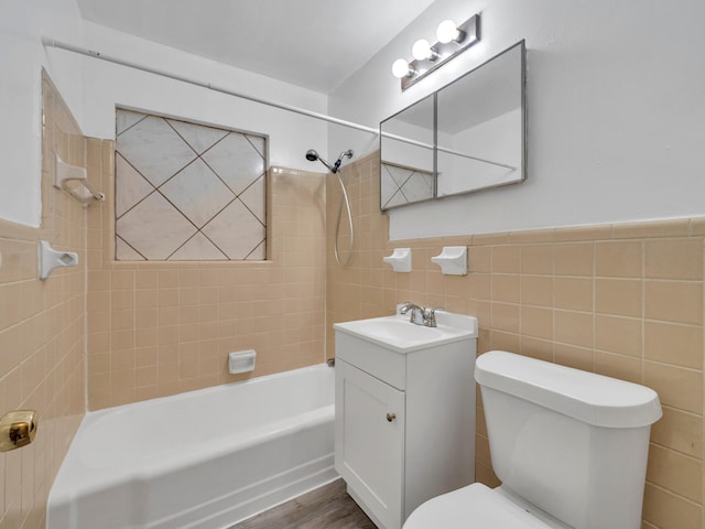 full bathroom featuring tile walls, vanity, wood-type flooring, tiled shower / bath, and toilet