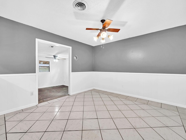 empty room featuring ceiling fan, a textured ceiling, and light tile patterned floors