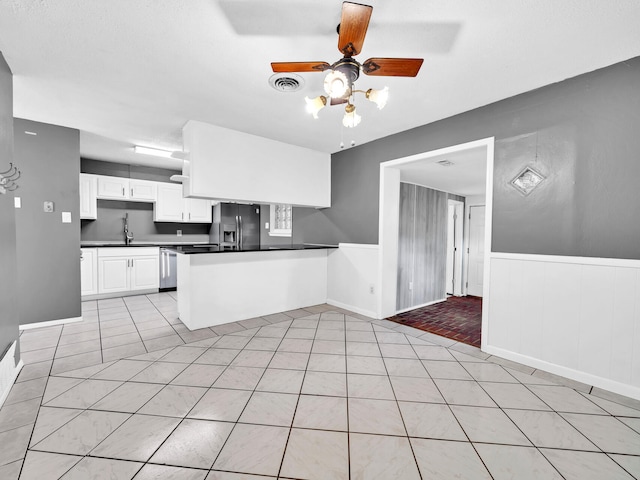 kitchen featuring light tile patterned flooring, sink, kitchen peninsula, stainless steel appliances, and white cabinets