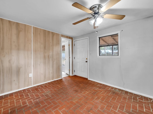 spare room featuring ceiling fan and wood walls