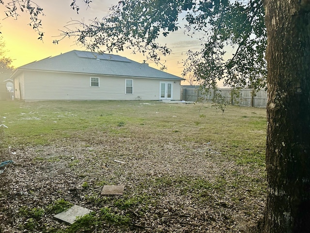 back house at dusk featuring a yard and french doors