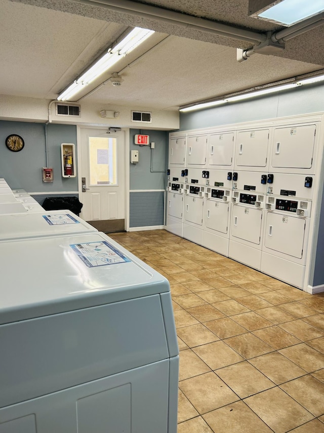 laundry area featuring washer and dryer, light tile patterned flooring, and stacked washer / drying machine