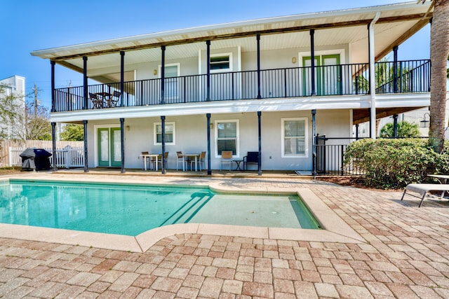 back of property featuring a patio and a fenced in pool