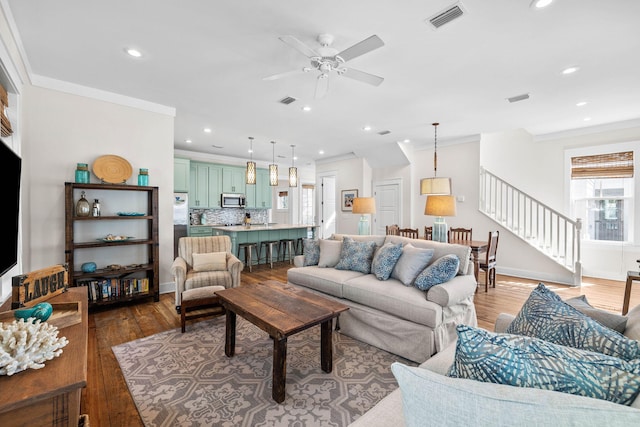 living room featuring wood-type flooring, ornamental molding, and ceiling fan