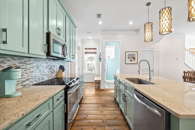 kitchen with appliances with stainless steel finishes, sink, light stone counters, and green cabinetry