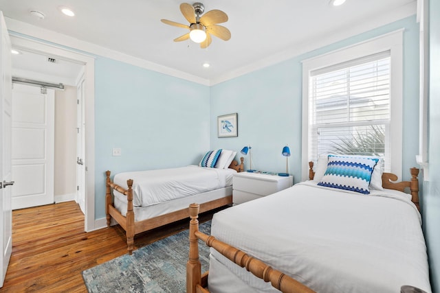 bedroom with ornamental molding, light hardwood / wood-style floors, a barn door, and ceiling fan