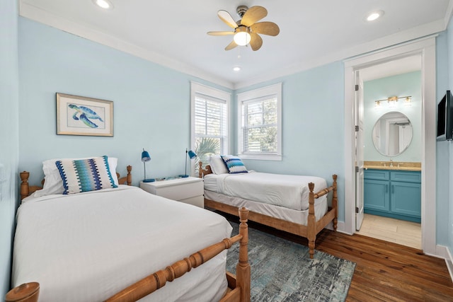 bedroom featuring ensuite bathroom, sink, crown molding, dark hardwood / wood-style flooring, and ceiling fan