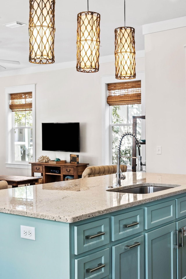 kitchen featuring crown molding, decorative light fixtures, sink, and light stone counters