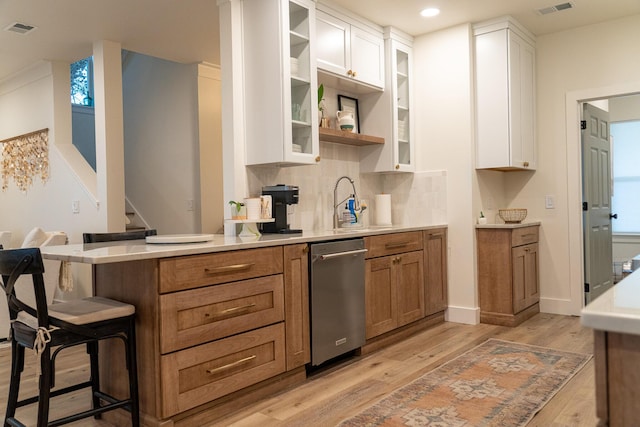 kitchen featuring white cabinetry, a kitchen breakfast bar, light hardwood / wood-style floors, and tasteful backsplash