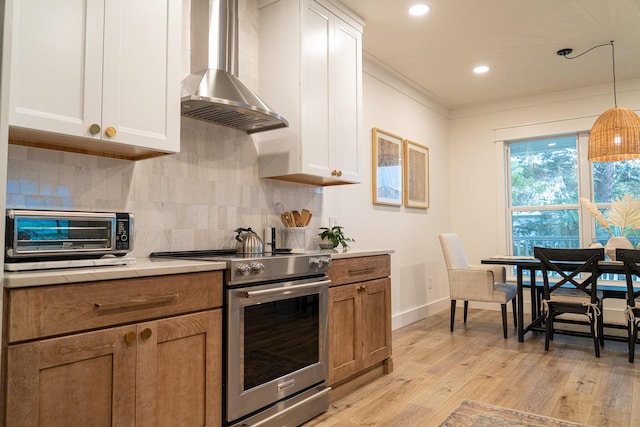 kitchen featuring pendant lighting, white cabinetry, stainless steel range with electric stovetop, light wood-type flooring, and wall chimney exhaust hood