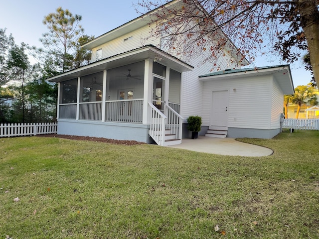 rear view of property featuring ceiling fan, a yard, a patio area, and a sunroom