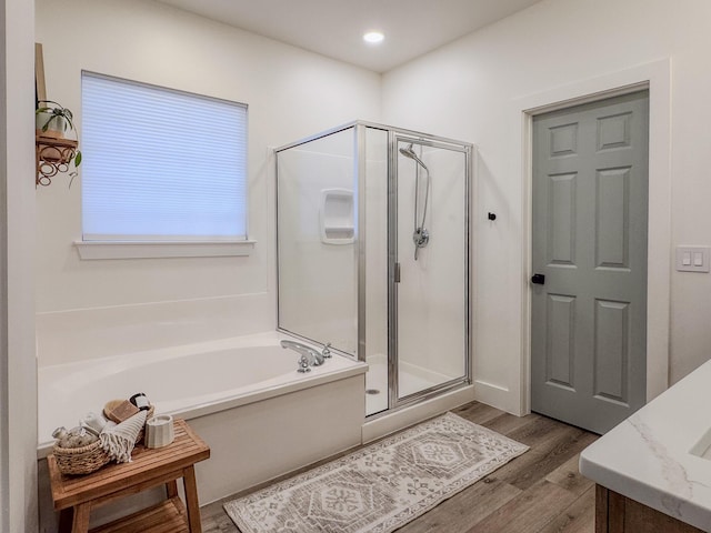 bathroom featuring vanity, plus walk in shower, and hardwood / wood-style floors