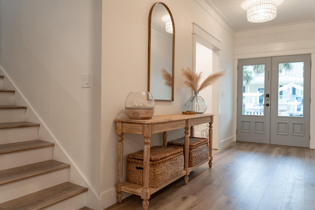 foyer entrance featuring french doors, crown molding, and light hardwood / wood-style flooring