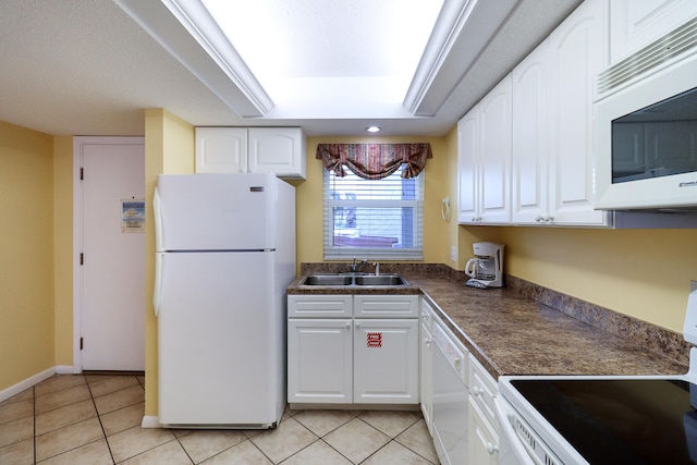 kitchen with white cabinetry, sink, light tile patterned floors, a tray ceiling, and white appliances