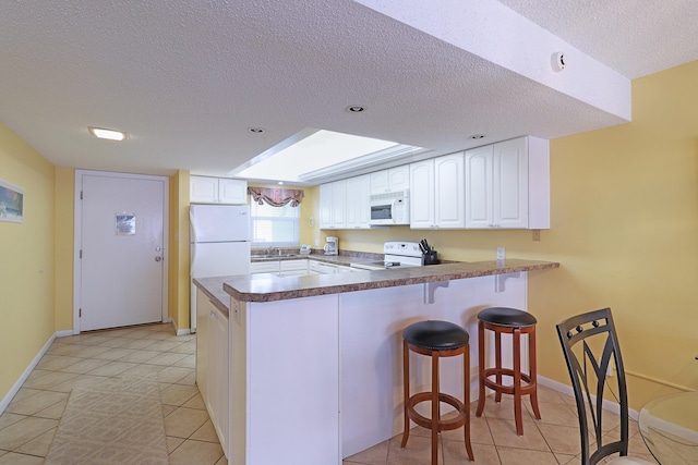 kitchen featuring light tile patterned flooring, white cabinetry, white appliances, kitchen peninsula, and a textured ceiling