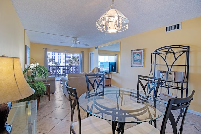 dining room featuring ceiling fan with notable chandelier, light tile patterned floors, and a textured ceiling