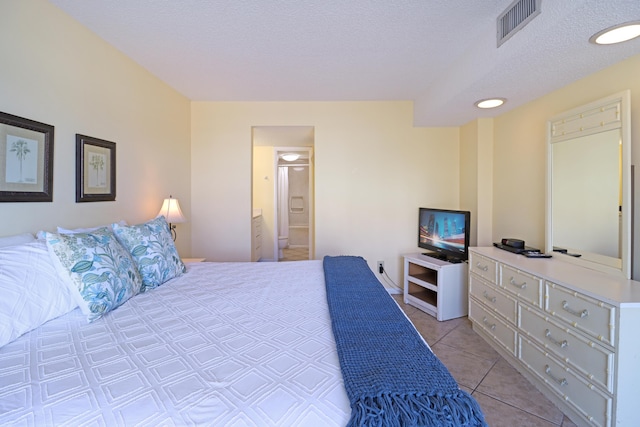 bedroom featuring ensuite bath, a textured ceiling, and light tile patterned flooring