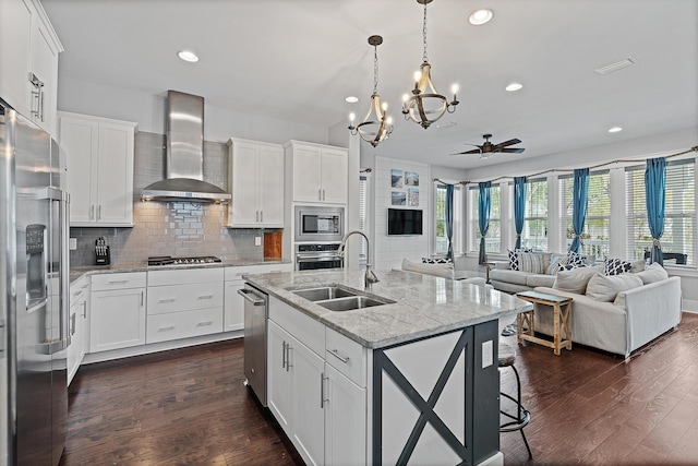 kitchen featuring stainless steel appliances, sink, wall chimney range hood, and white cabinets