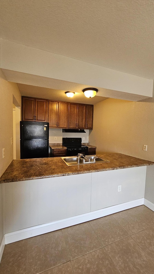 kitchen with dark tile patterned floors, kitchen peninsula, and black appliances