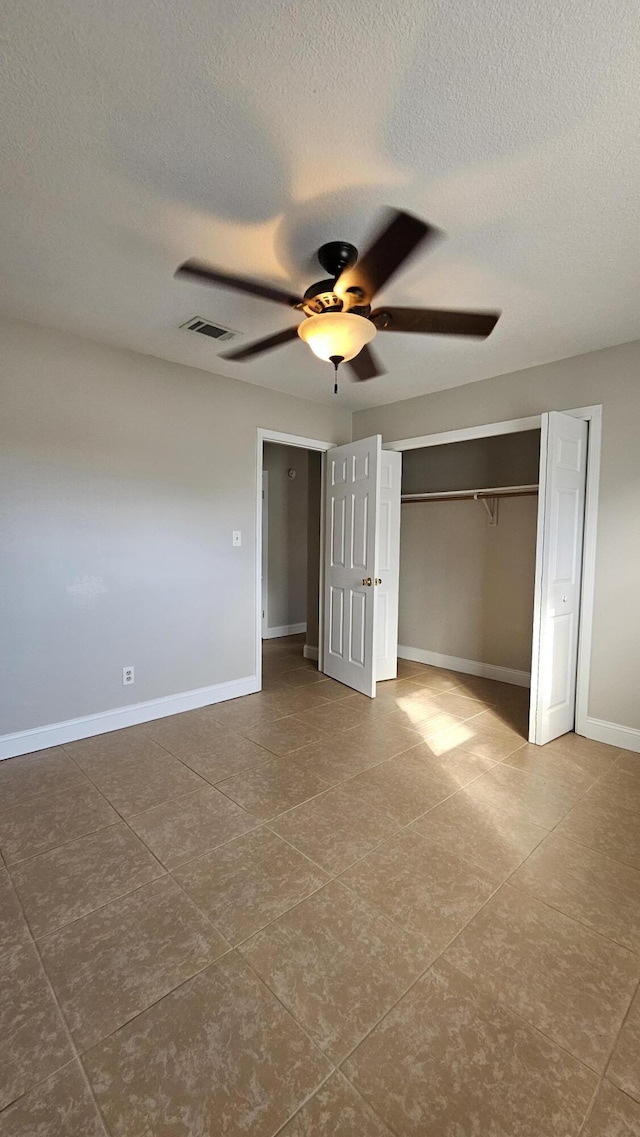 unfurnished bedroom featuring a textured ceiling, ceiling fan, and a closet