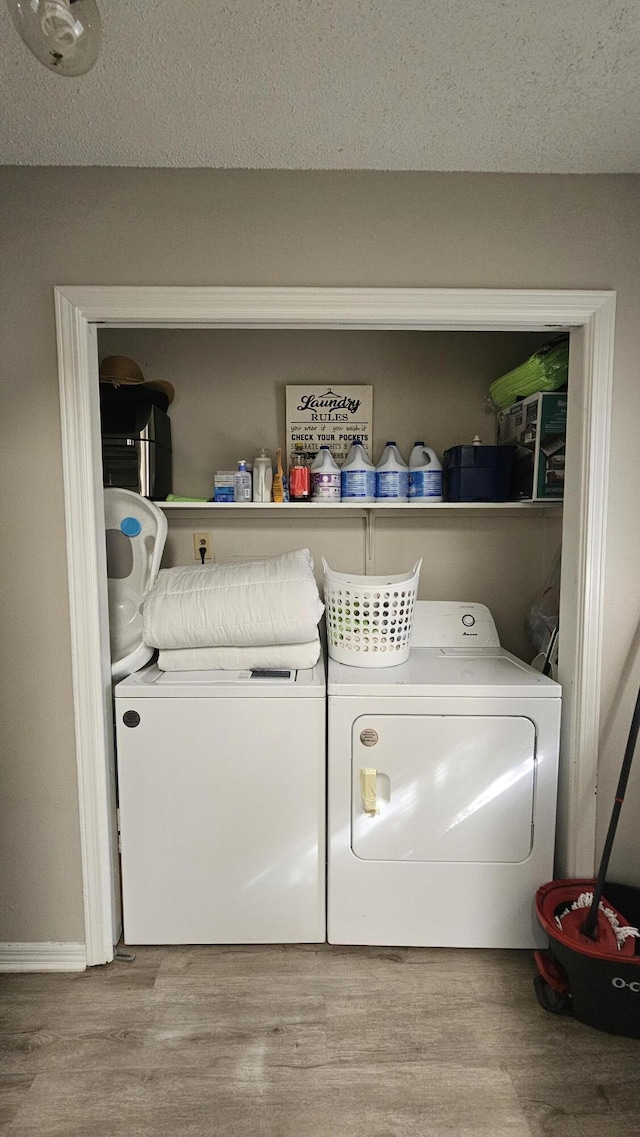 clothes washing area featuring washer and clothes dryer, light hardwood / wood-style flooring, and a textured ceiling