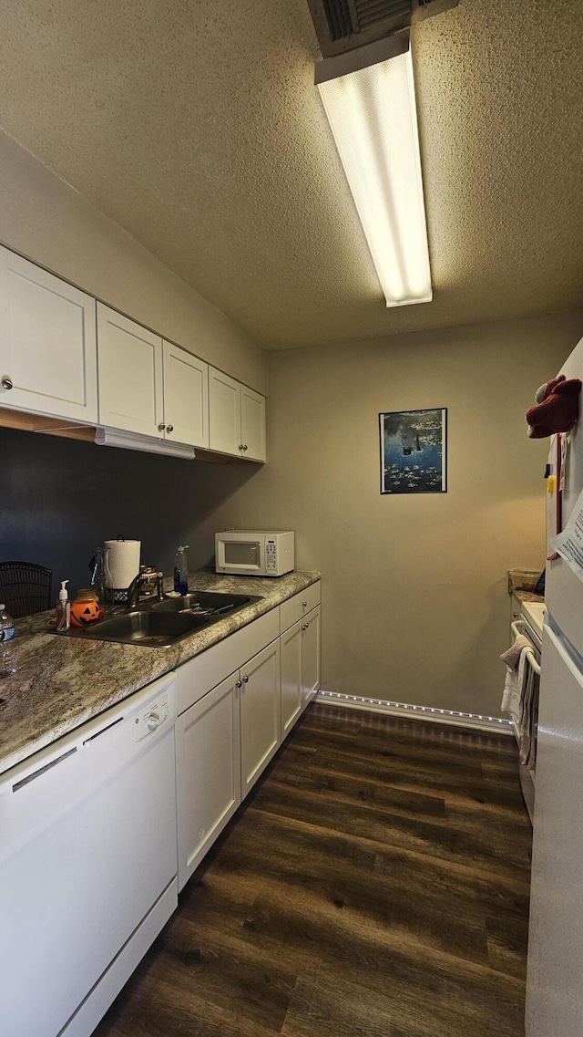 kitchen with dark wood-type flooring, white appliances, a textured ceiling, and white cabinets