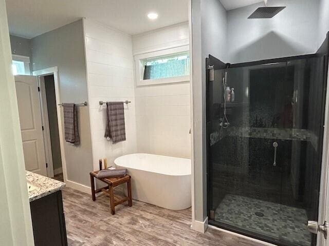 bathroom with vanity, hardwood / wood-style floors, shower with separate bathtub, and tile walls