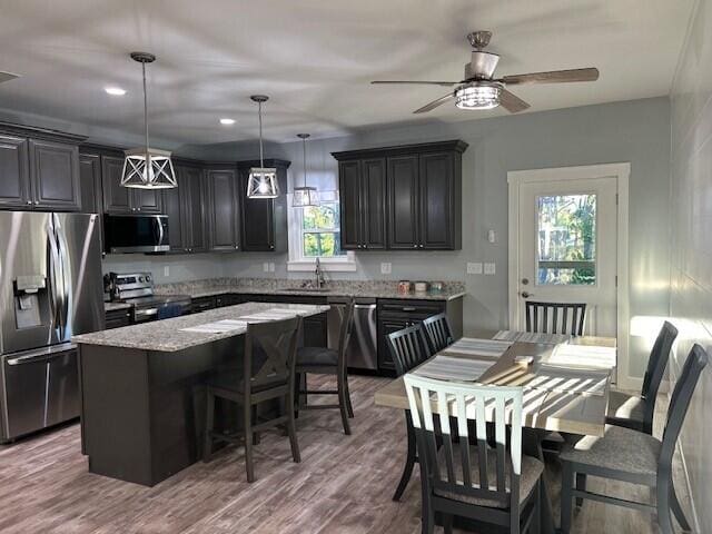 kitchen featuring stainless steel appliances, a kitchen island, and hanging light fixtures