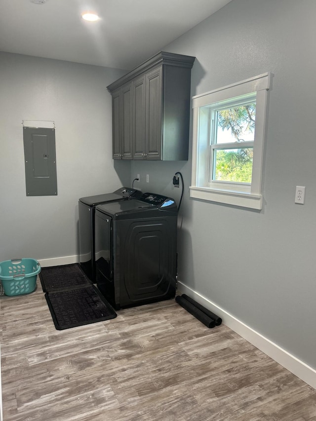 washroom with light hardwood / wood-style flooring, electric panel, and washing machine and clothes dryer